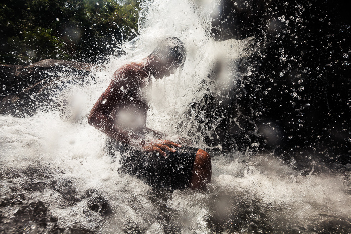 A man sits beneath a waterfall in Koh Kong Cambodia.